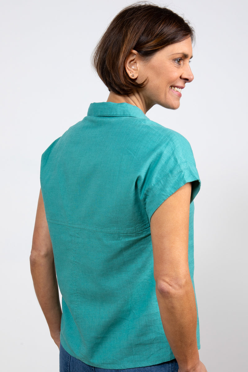 Lily & Me Sky Shirt. A short-sleeved, linen shirt with a button-down front, fixed turn back cuffs, and a plain teal design.