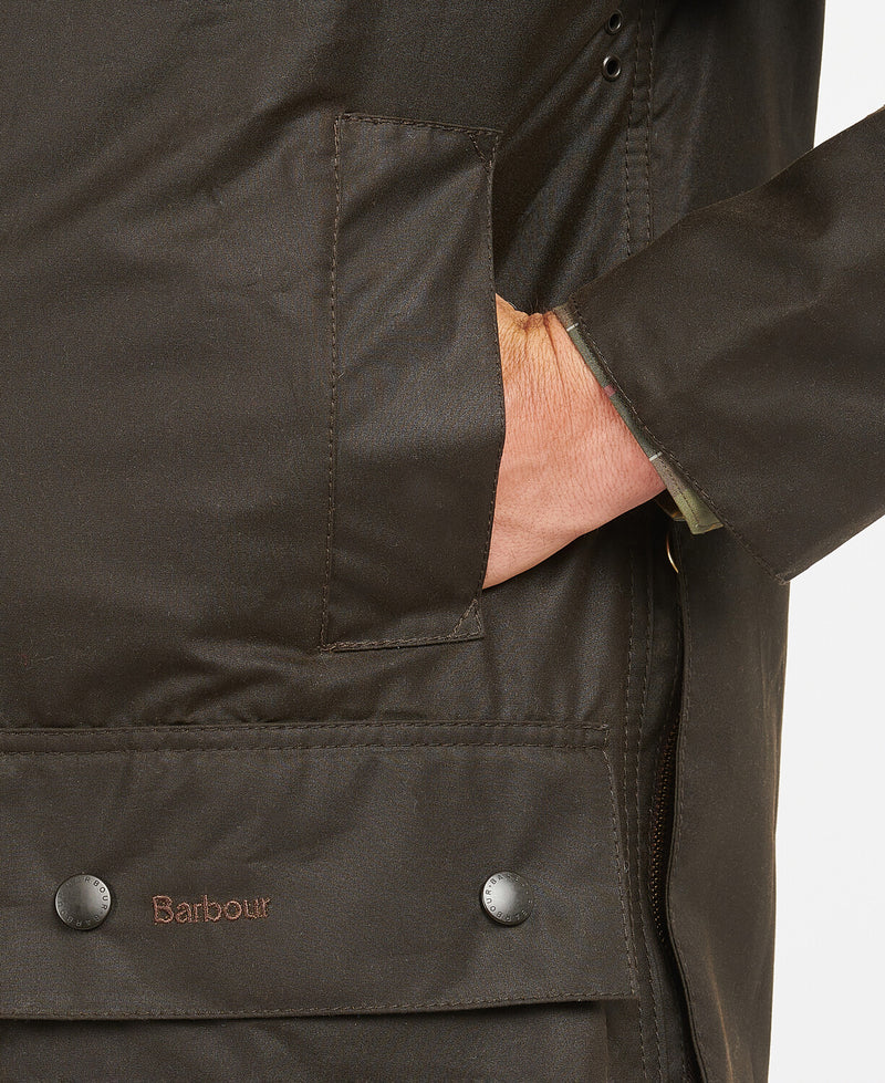 An image of a male model wearing the Barbour Classic Beaufort Wax Jacket in the colour Olive.