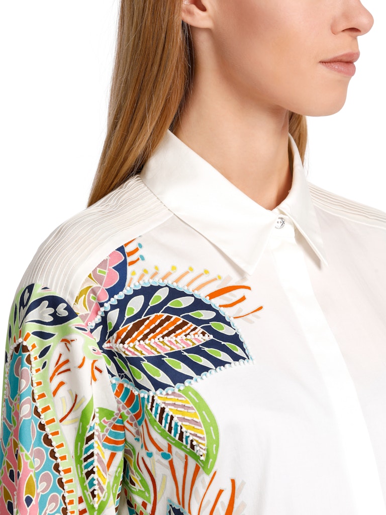 Marc Cain Beaded Floral Blouse. An A-line blouse with wide sleeves and kent style collar. This shirt has a multicoloured print with embroidery and a side seam slit.