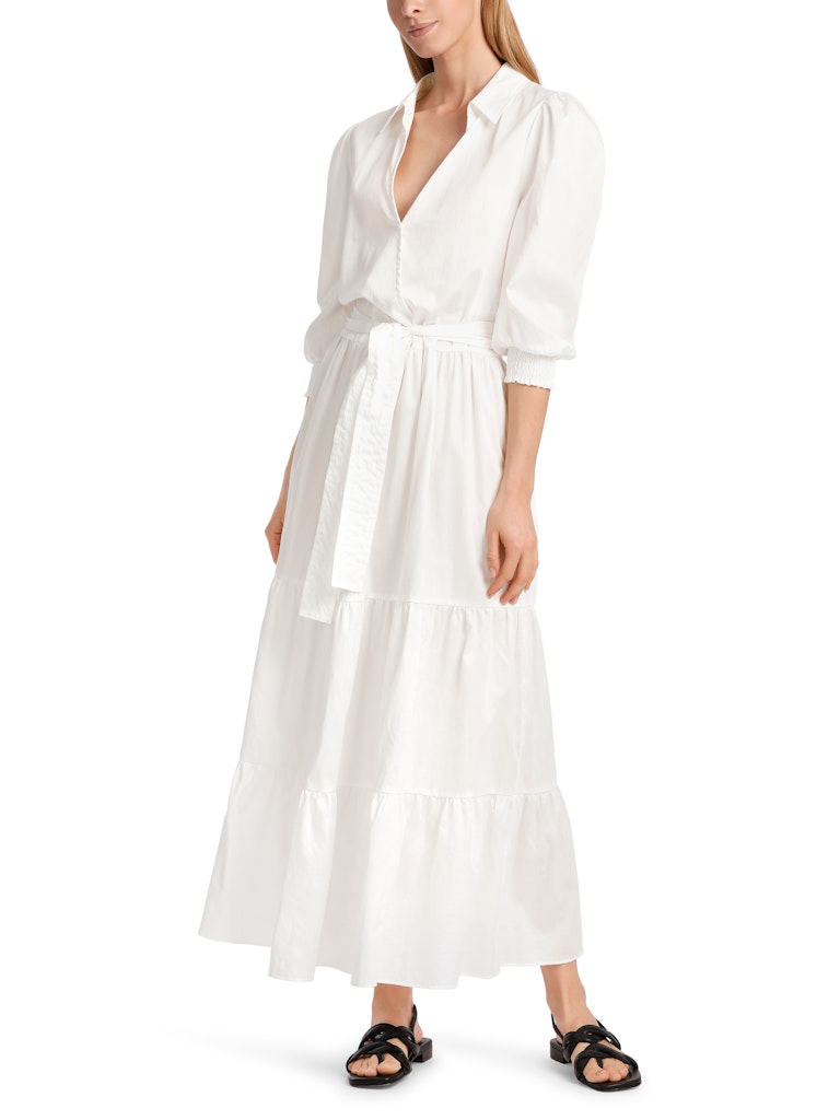 Marc Cain Tiered Maxi Dress. A maxi length dress with 3/4 length sleeves, tiered skirt and kent style collar. This dress is off-white and has a tie waist detail.