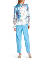 Marc Cain Long Sleeve Pattern Blouse. A relaxed fit blouse with long sleeves, featuring a ruffle detail. This top has a round neck with slit detail and back zip. The design has an underwater themed print in a mix of blue and red.