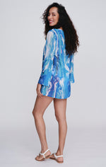 Pia Rossini Mauritius Cover Up. A midi length, long sleeve cover up in lightweight fabric with blue ocean print. This cover up also has embellishment detail.