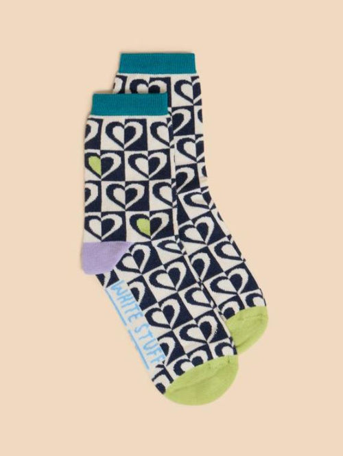 White Stuff Graphic Heart Sock. An ankle sock with a retro black & white heart design, green toe, purple heel, and subtle green detail throughout the design.