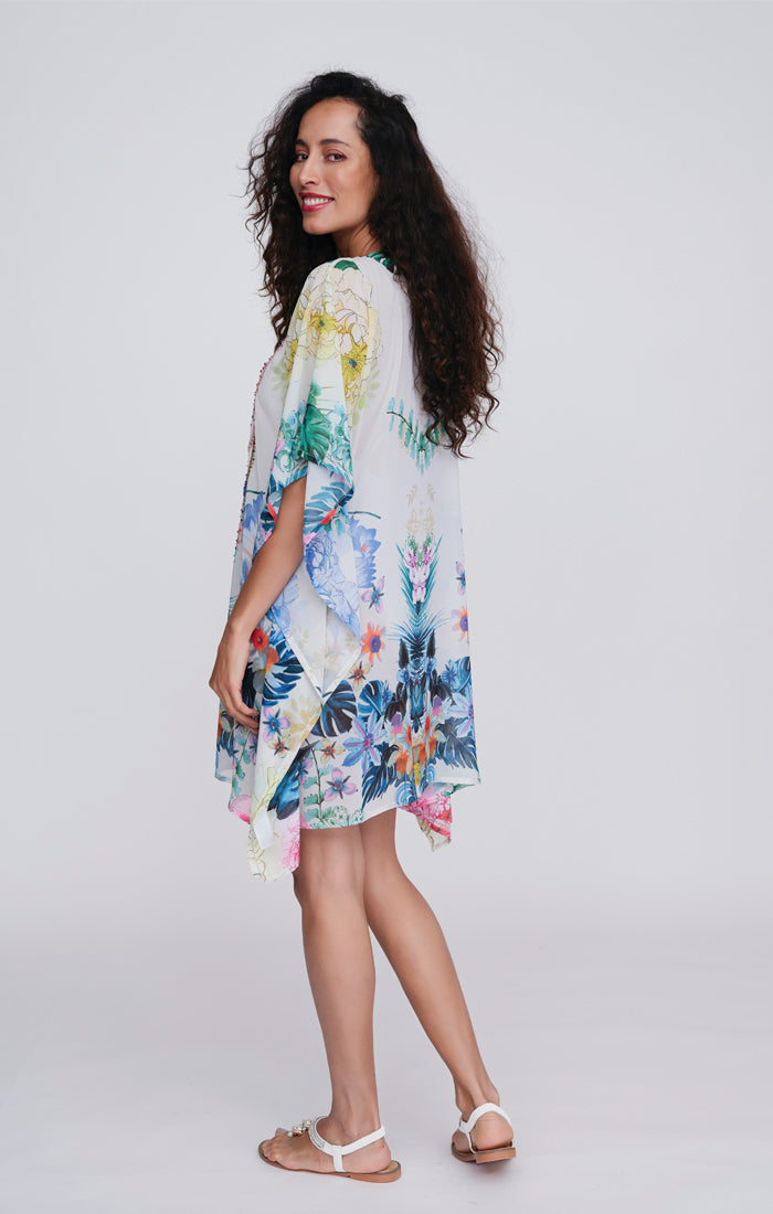 Pia Rossini Paradiso Cover Up. A mid-length, 3/4 sleeve cover up made of lightweight fabric with embellishment and multi-coloured floral print.