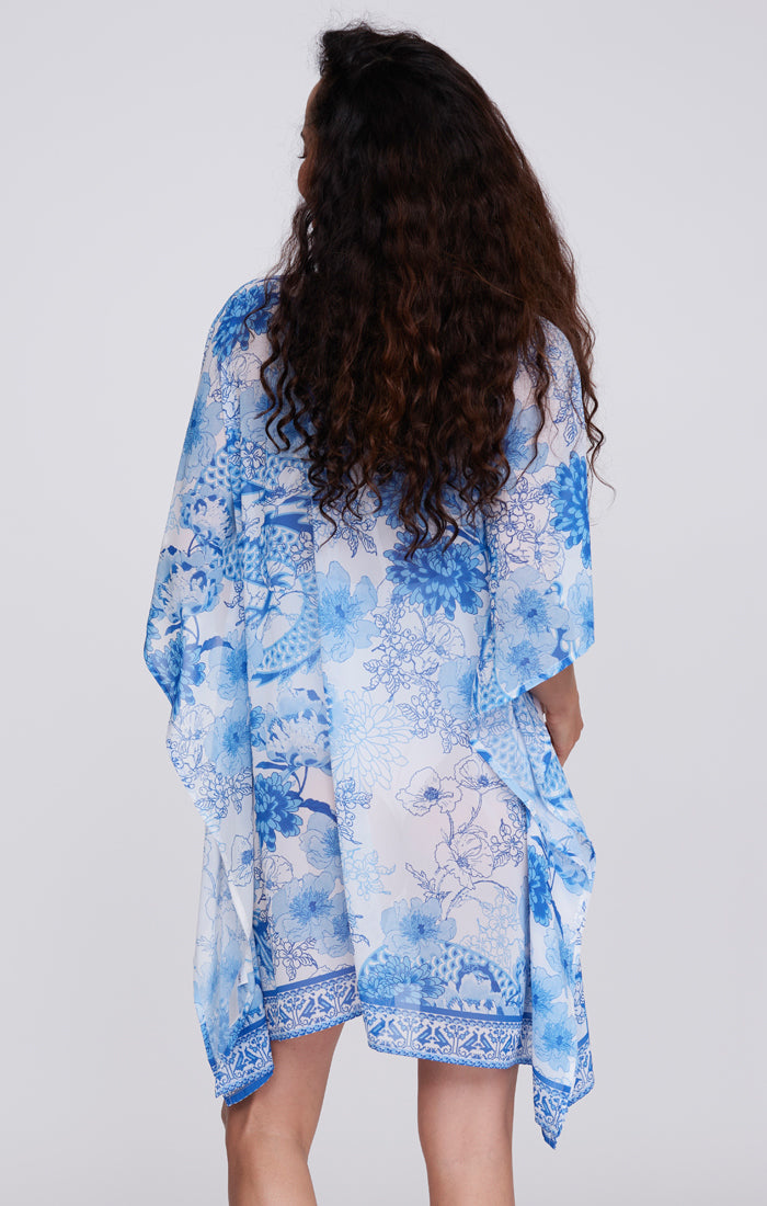 Pia Rossini Salerno Cover Up. A midi-length cover up with 3/4 length sleeves and V-neckline, This cover up is complete with embellishments and blue tile print lightweight fabric.