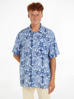 An image of a model wearing the Tommy Hilfiger Palm Print Tie-Dye Linen Relaxed Short Sleeve Shirt in the colour Well Water.