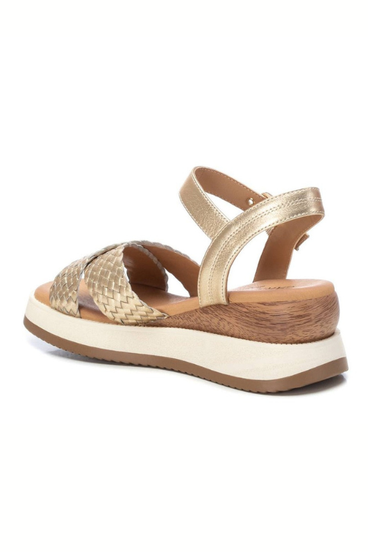 Carmela Sandal. A pair of gold platform sandals made from leather, featuring a shiny woven design. These sandals have a buckle closure and non-slip sole.