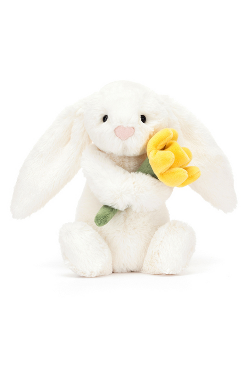 Jellycat Daffodil Bunny Little. A cream coloured bunny soft toy holding a yellow daffodil.