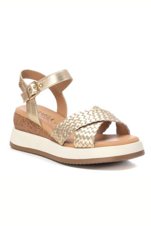 Carmela Sandal. A pair of gold platform sandals made from leather, featuring a shiny woven design. These sandals have a buckle closure and non-slip sole.