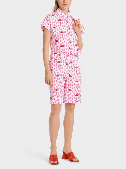 Marc Cain Flamingo Short Sleeve Blouse. An oversized fit blouse with kimono sleeves, Kent collar, and button placket. This blouse features a pink flamingo print.