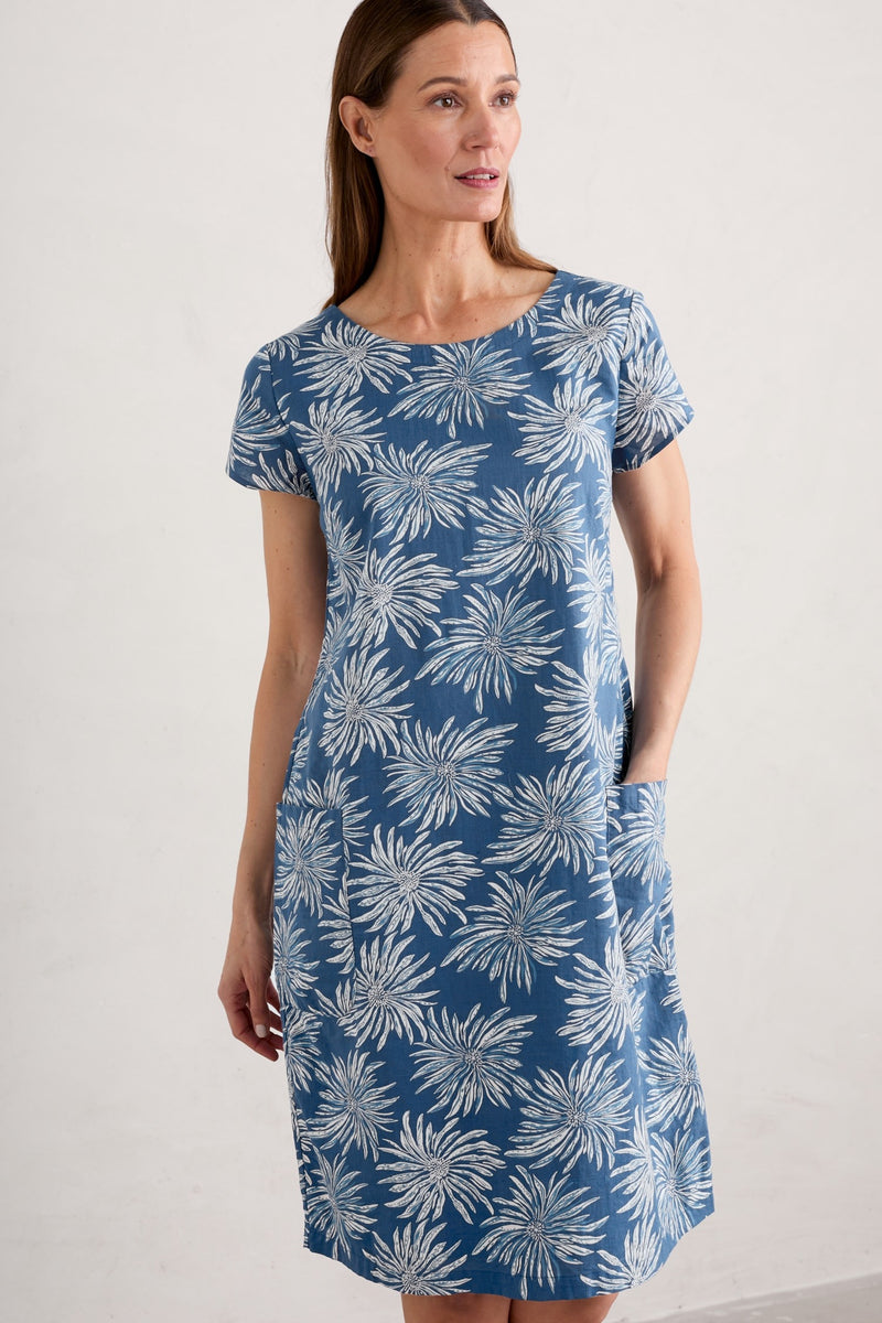 An image of a female model wearing the Seasalt River Cove Dress in the colour Flower Dark Voyage.