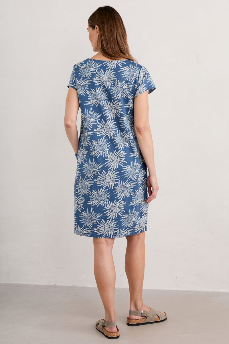 An image of a female model wearing the Seasalt River Cove Dress in the colour Flower Dark Voyage.